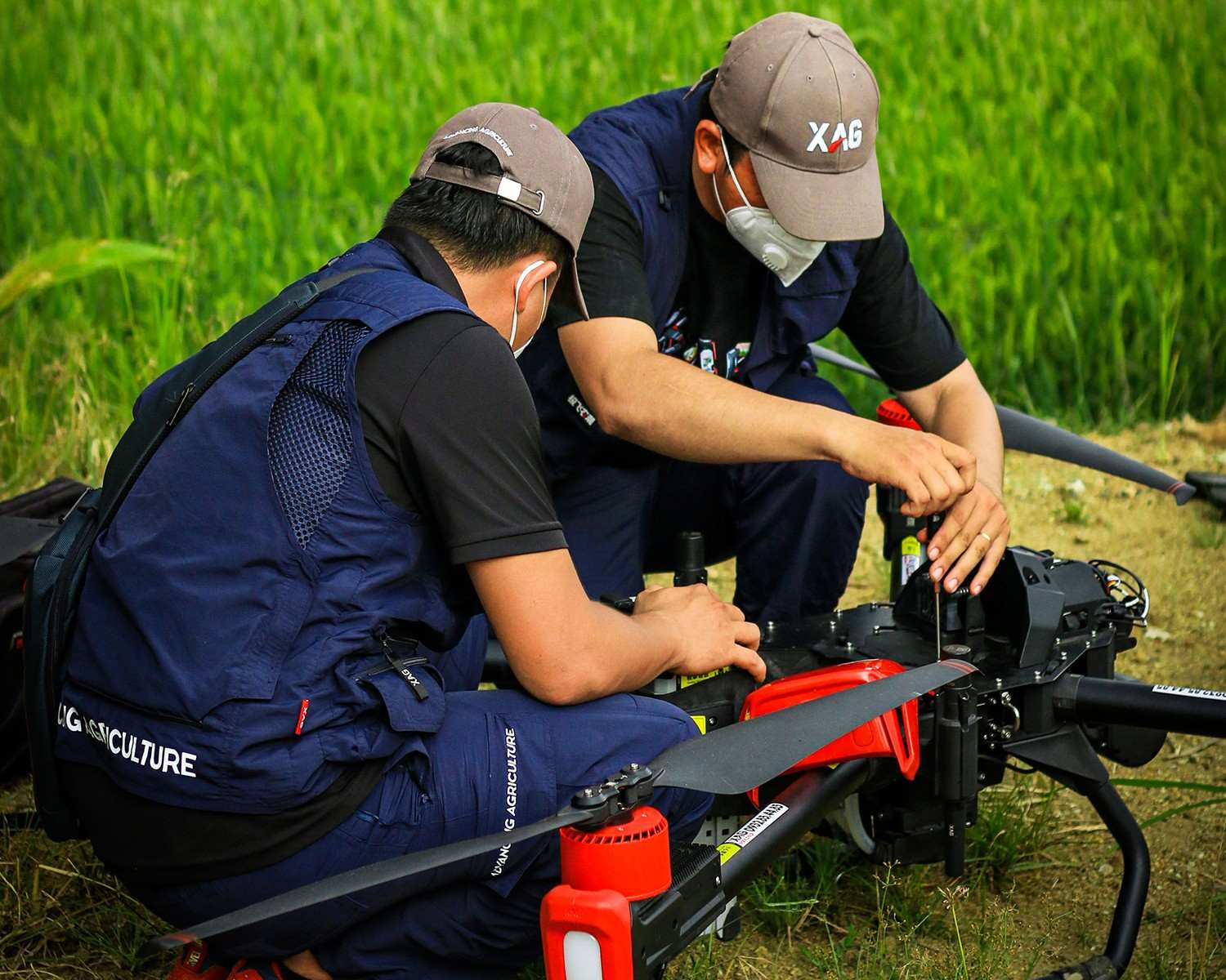 two young drone pilots are carefully conducting maintenance before taking the new agricultural skywalker to rice field demonstration.