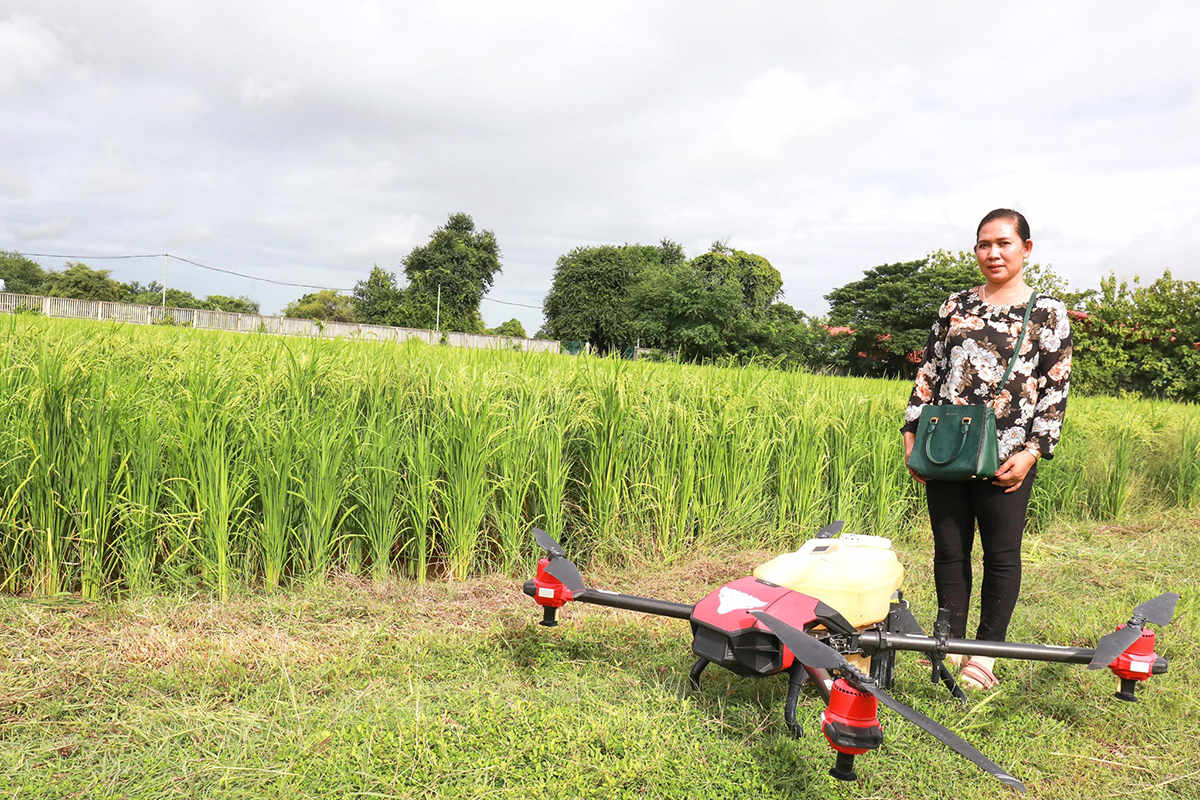 tou kousal stood beside a paddy field with one of her drones